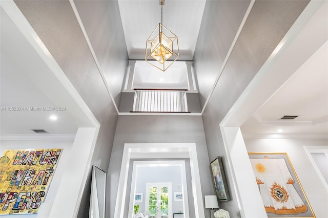 entryway with a high ceiling, crown molding, and a notable chandelier