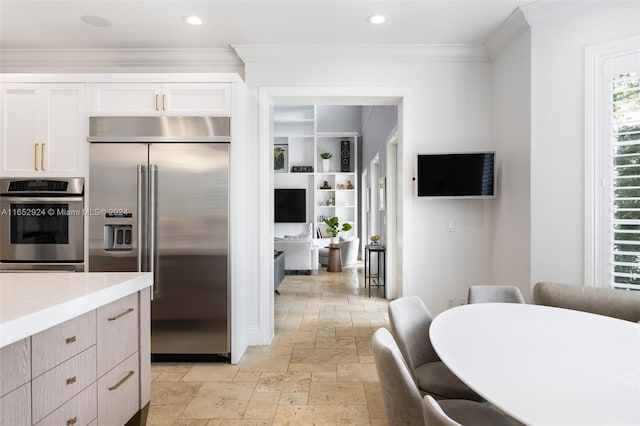 kitchen with white cabinetry, built in refrigerator, and ornamental molding