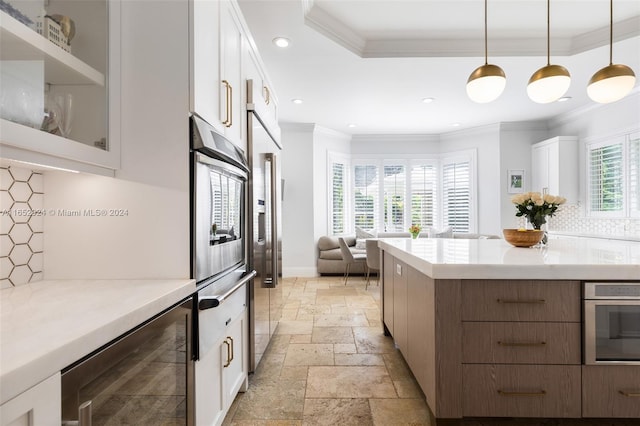 kitchen with backsplash, white cabinets, oven, decorative light fixtures, and beverage cooler