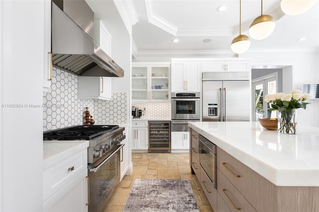 kitchen with white cabinets, wall chimney range hood, and premium appliances