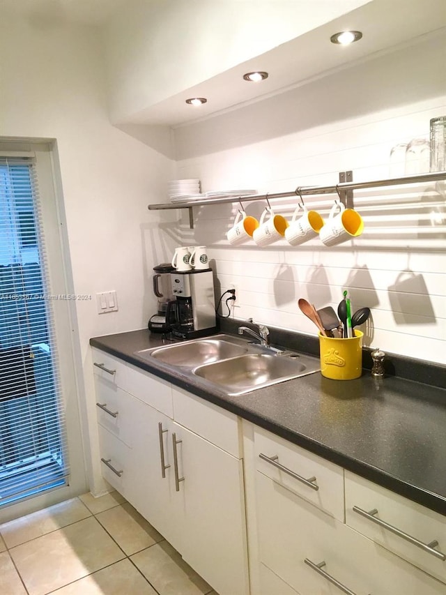 kitchen with light tile patterned floors, decorative backsplash, white cabinetry, and sink