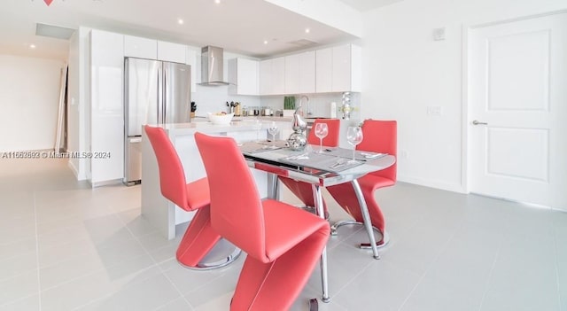 kitchen with white cabinets, wall chimney exhaust hood, stainless steel refrigerator, and light tile patterned flooring