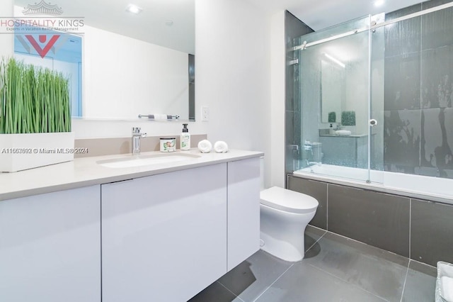 full bathroom featuring tile patterned flooring, vanity, toilet, and combined bath / shower with glass door