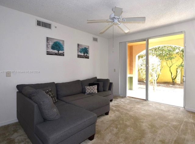 living room featuring ceiling fan, light colored carpet, and a textured ceiling