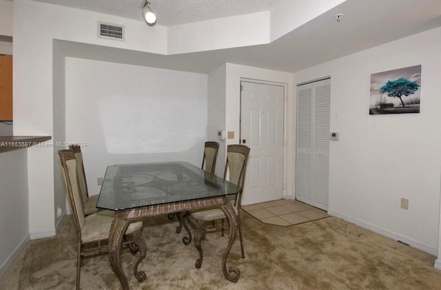 dining area featuring a textured ceiling and light colored carpet