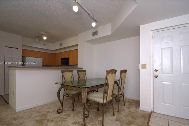 dining area with light carpet, a textured ceiling, and rail lighting