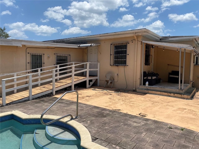 rear view of house with a wooden deck and a patio