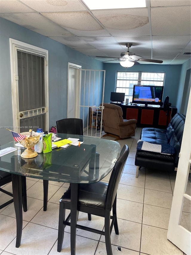 tiled dining space featuring ceiling fan and a drop ceiling