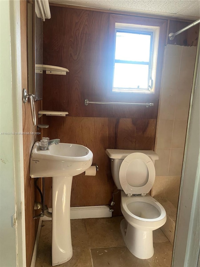 bathroom with tiled shower, toilet, and tile patterned floors