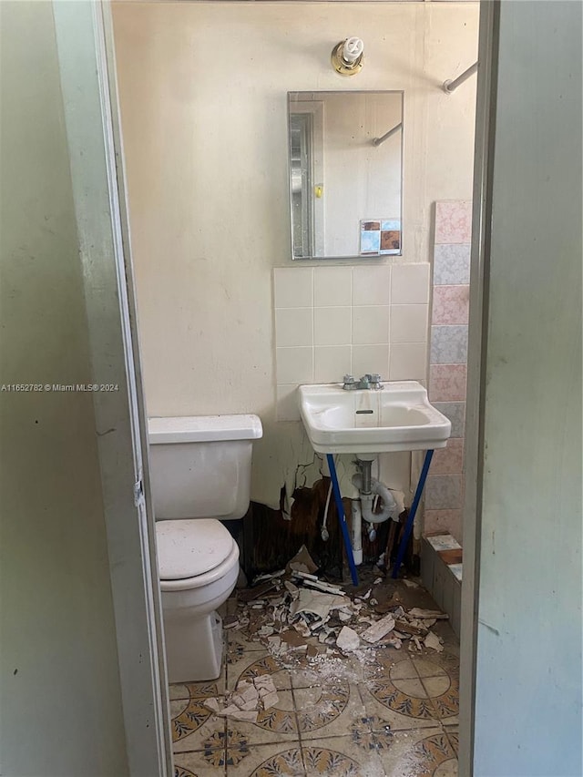 bathroom featuring tile walls, tile patterned flooring, and toilet