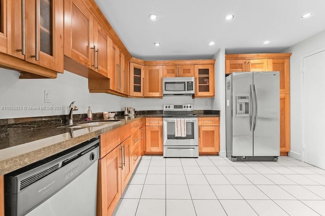 kitchen with light tile patterned flooring, dark stone countertops, sink, and appliances with stainless steel finishes