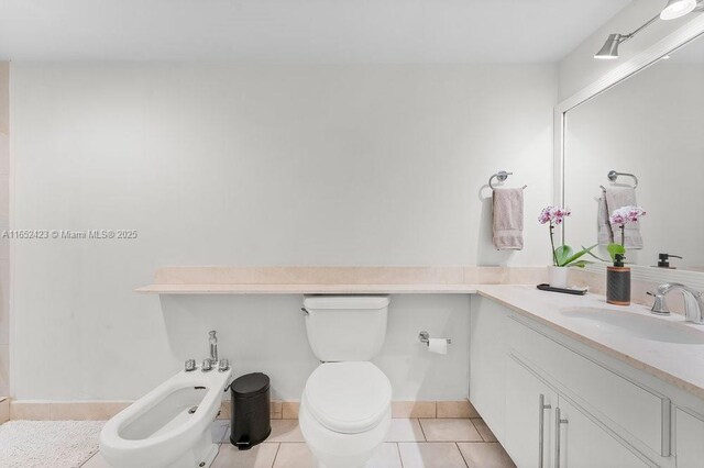 bathroom with toilet, vanity, tile patterned floors, and a bidet