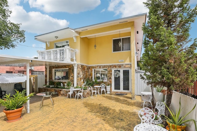 back of property featuring a balcony, a hot tub, and a patio area