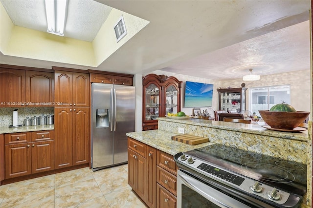 kitchen featuring light stone counters, a textured ceiling, appliances with stainless steel finishes, and light tile patterned floors