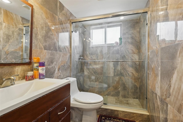 bathroom with tile walls, walk in shower, vanity, and toilet