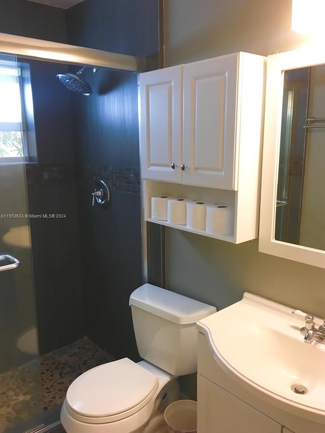 bathroom featuring walk in shower, toilet, and vanity