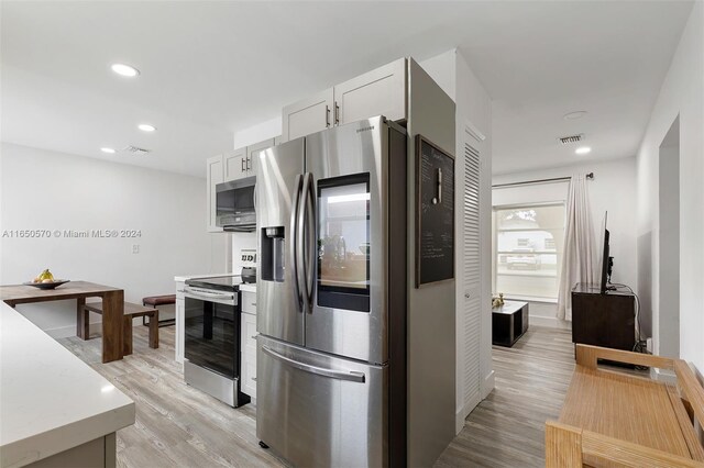 kitchen featuring light wood-type flooring, white cabinets, and stainless steel appliances