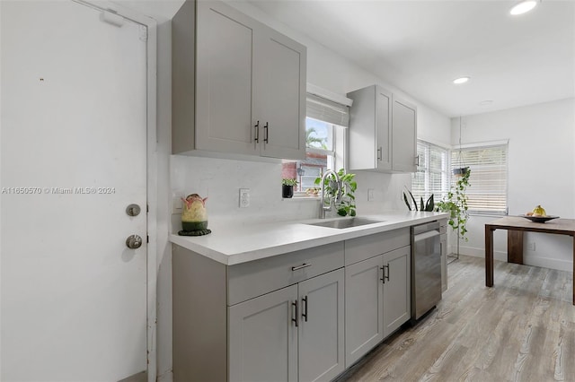 kitchen with dishwasher, light wood-type flooring, sink, gray cabinets, and decorative backsplash