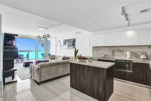 kitchen featuring oven, a center island, sink, decorative backsplash, and white cabinets