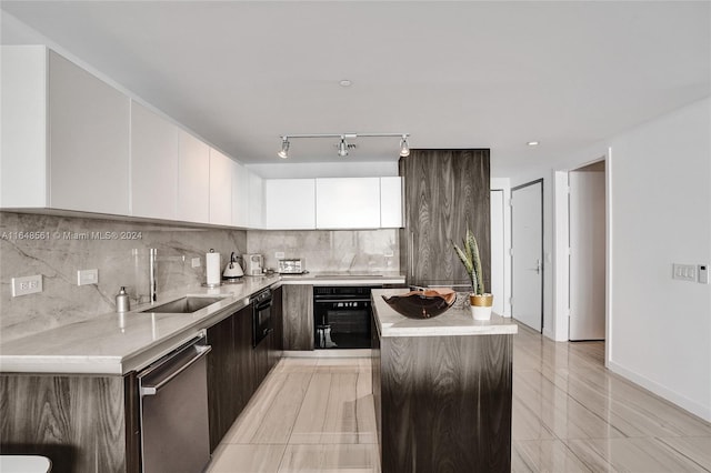 kitchen with dishwasher, backsplash, sink, white cabinetry, and black oven