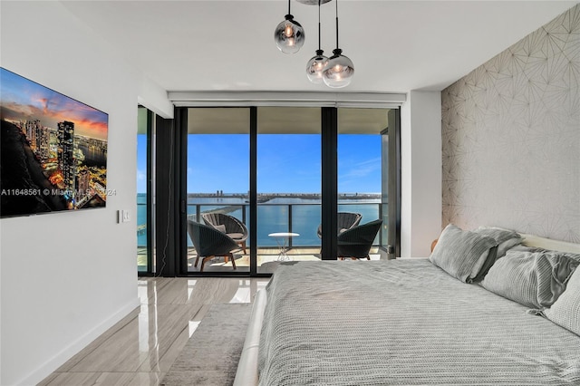 bedroom featuring a water view, multiple windows, expansive windows, and access to exterior