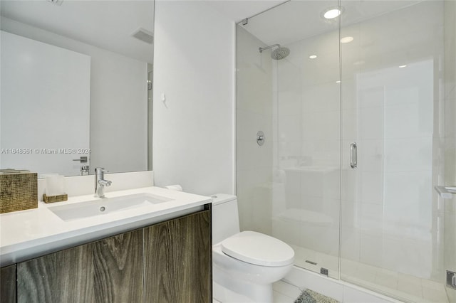 bathroom with a shower with door, vanity, toilet, and tile patterned flooring