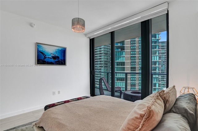 bedroom with a chandelier, expansive windows, light wood-type flooring, and multiple windows