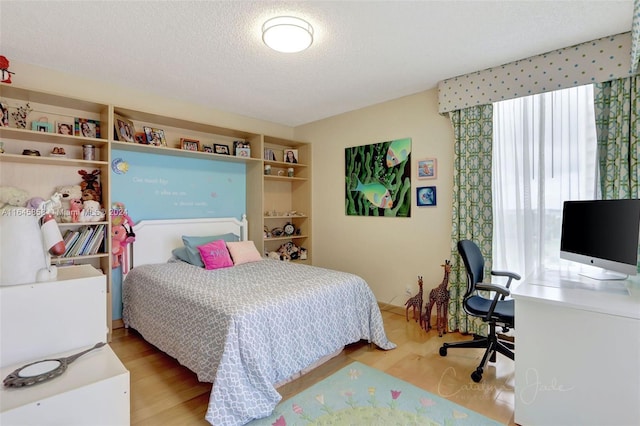 bedroom with a textured ceiling and light hardwood / wood-style floors