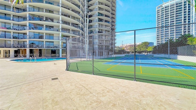 view of tennis court featuring a community pool