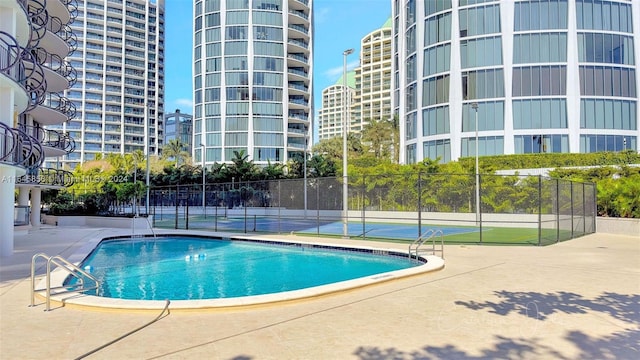 view of swimming pool featuring tennis court