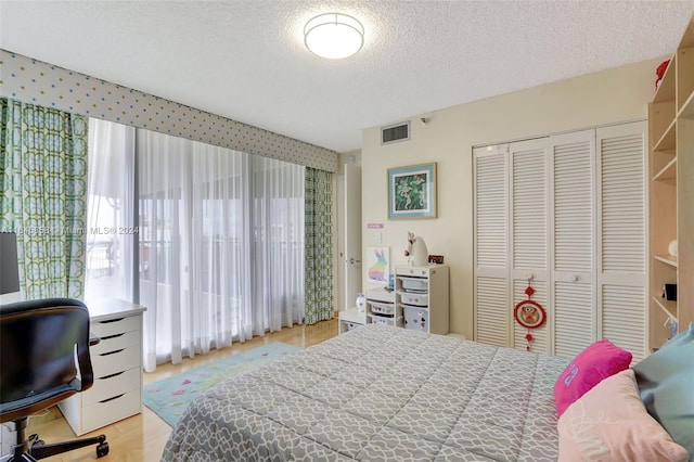 bedroom with a textured ceiling, light hardwood / wood-style flooring, and a closet