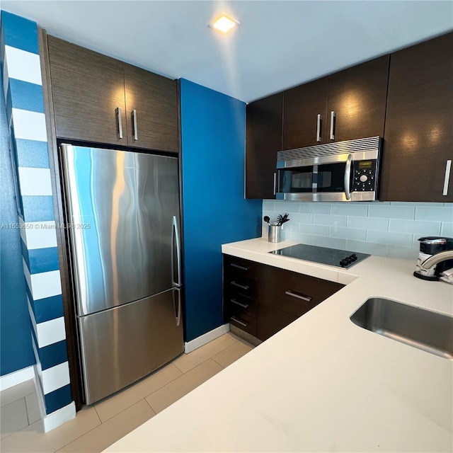 kitchen with appliances with stainless steel finishes, tasteful backsplash, dark brown cabinets, and sink