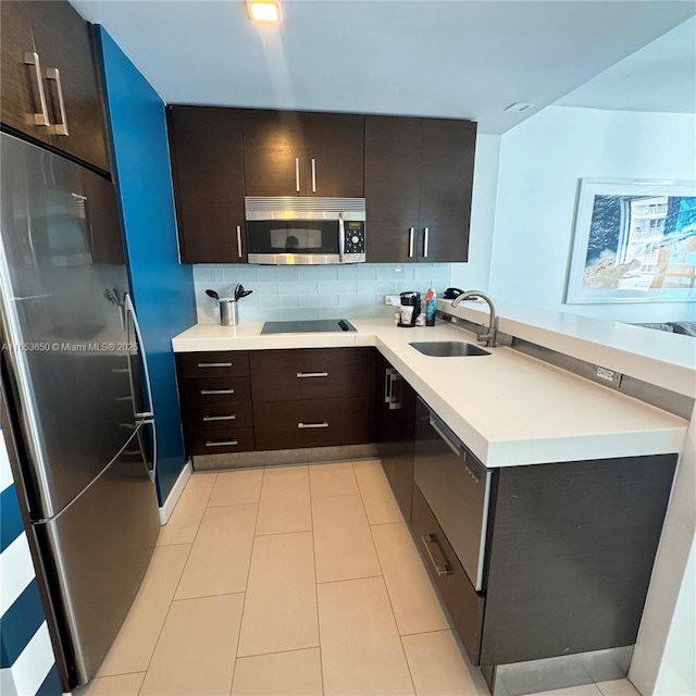 kitchen with appliances with stainless steel finishes, dark brown cabinetry, tasteful backsplash, and sink