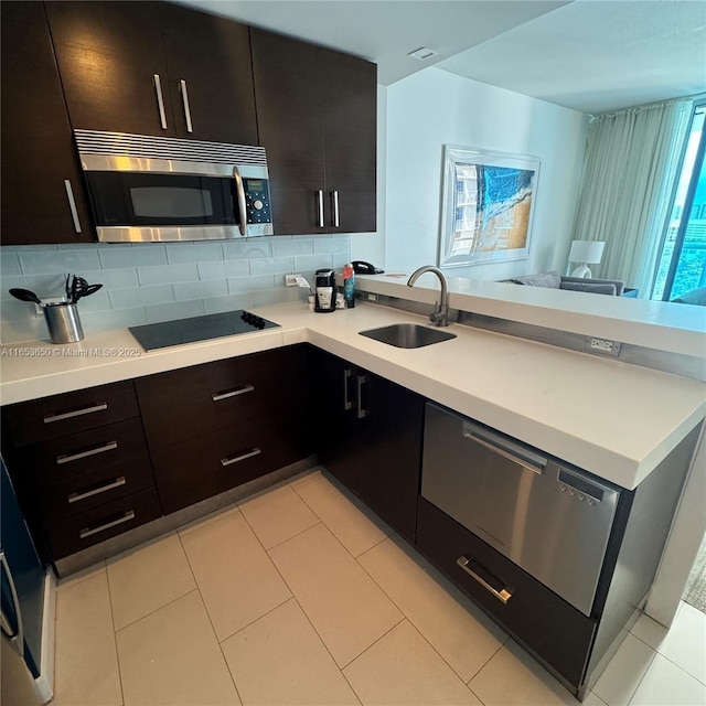 kitchen with decorative backsplash, dark brown cabinets, black electric cooktop, and sink