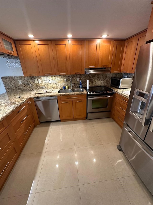 kitchen featuring backsplash, light tile patterned floors, light stone counters, stainless steel appliances, and sink