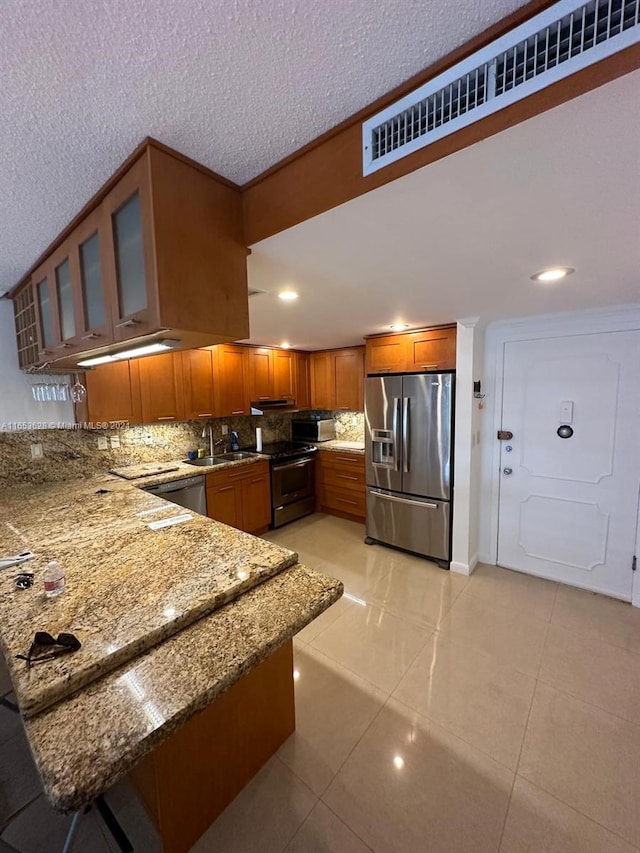 kitchen with light tile patterned floors, stainless steel appliances, sink, dark stone counters, and tasteful backsplash