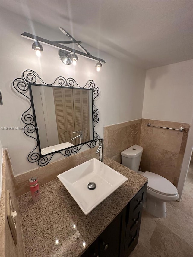 bathroom featuring tile walls, toilet, and vanity