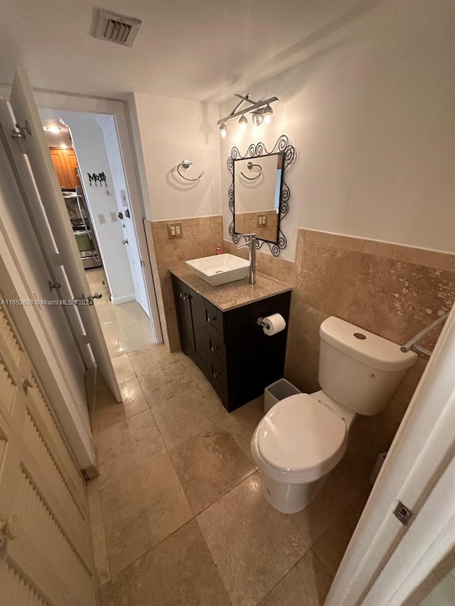 bathroom featuring vanity, tile walls, toilet, and tile patterned floors