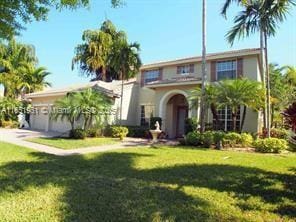 mediterranean / spanish home with a front yard and an attached garage