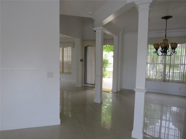 interior space featuring a chandelier, tile patterned floors, crown molding, and decorative columns