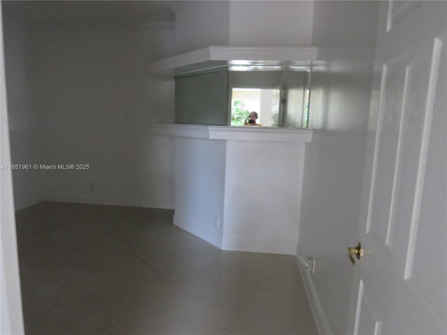 tiled empty room featuring baseboards