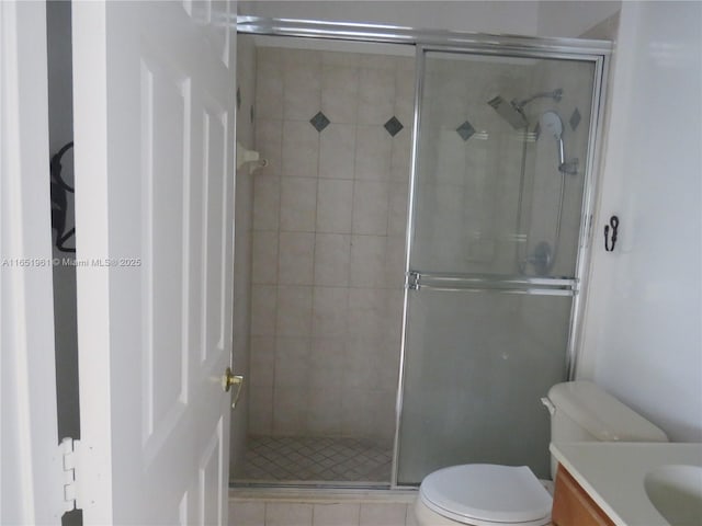 bathroom featuring vanity, toilet, and a stall shower