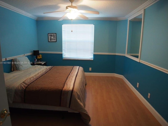 bedroom with a textured ceiling, wood finished floors, baseboards, and ornamental molding