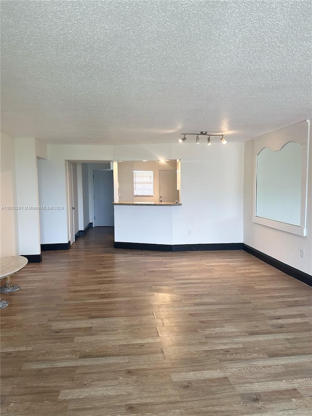 spare room with dark wood-type flooring, rail lighting, and a textured ceiling