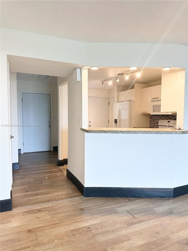 kitchen with wood-type flooring, light stone counters, white appliances, and white cabinets