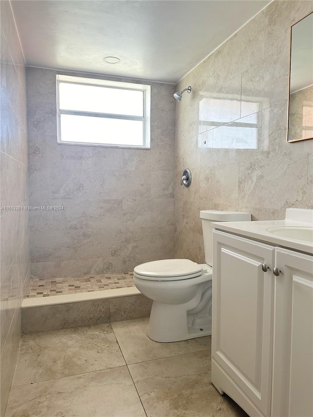 bathroom with tiled shower, toilet, and vanity