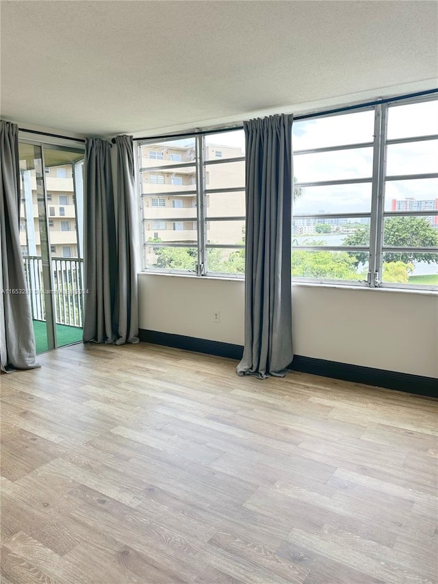 spare room featuring a wealth of natural light, light hardwood / wood-style flooring, and a textured ceiling