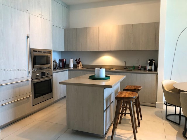 kitchen featuring a center island, stainless steel appliances, sink, light tile patterned flooring, and a breakfast bar