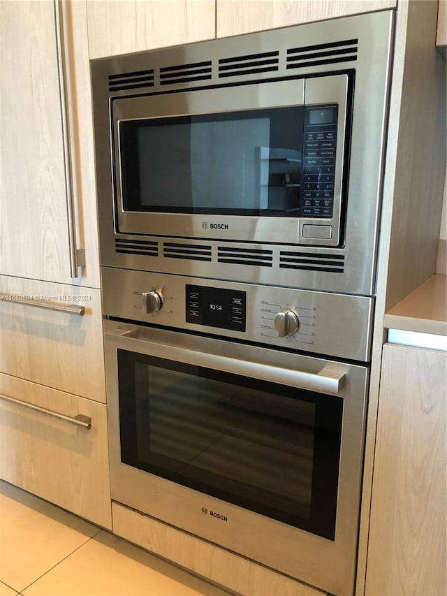 details with light brown cabinetry, stainless steel appliances, and light tile patterned flooring