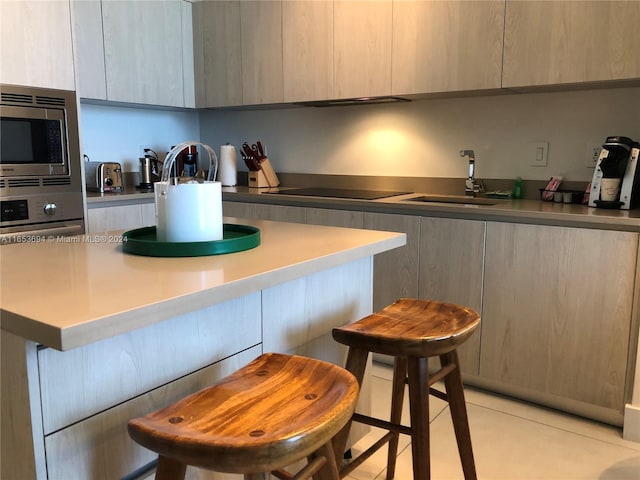 kitchen featuring light tile patterned floors, light brown cabinetry, stainless steel appliances, and sink